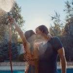 Couple having fun pour each other with garden hose