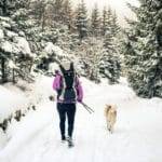 Woman walking in winter forest with dog