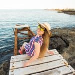 Young happy woman sitting on wooden pier and laughing.