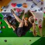 Young woman bouldering on overhanging wall in climbing gym
